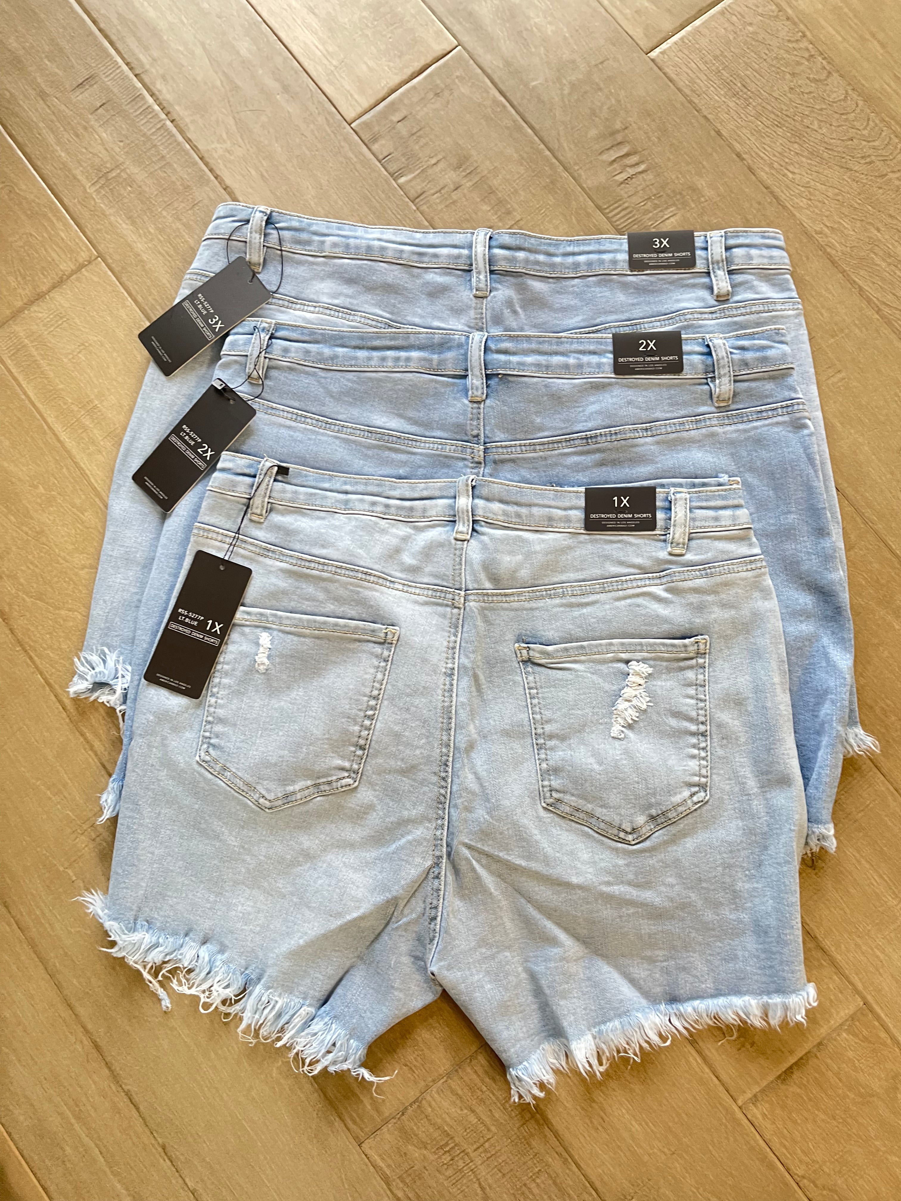 1X 2X and 3X high-waisted light wash denim shorts from Adrienne Rebecca Boutique displayed on a wooden floor