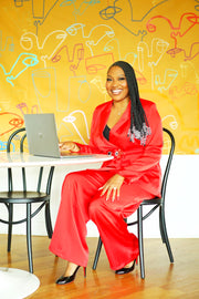 Confident plus size woman smiling in the Boardroom Blaze red pantsuit with wide-leg trousers and tailored blazer, styled for a boardroom-ready yet chic look – Adrienne Rebecca Boutique.